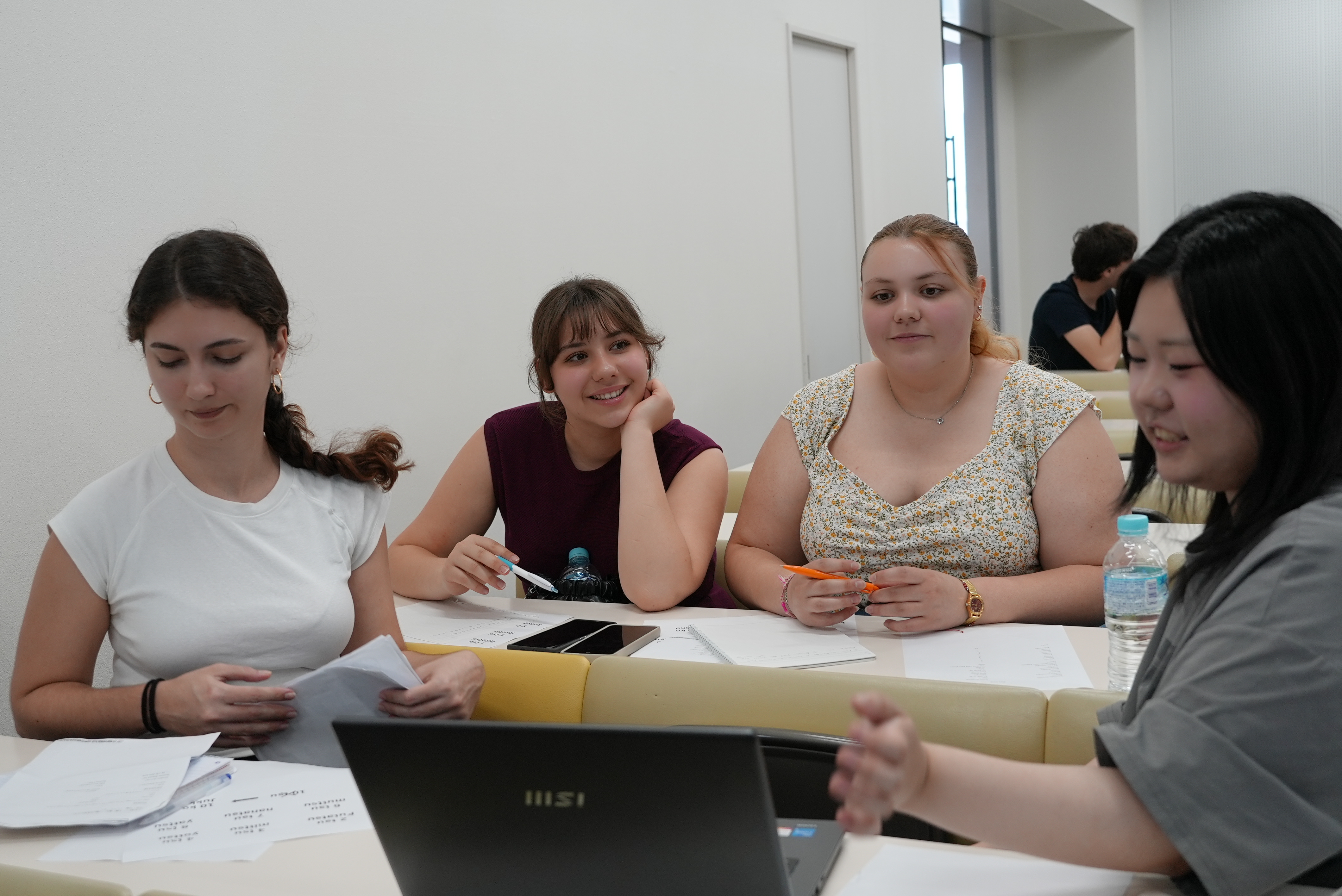 Trois étudiants échangent autour d’une table dans une salle lumineuse